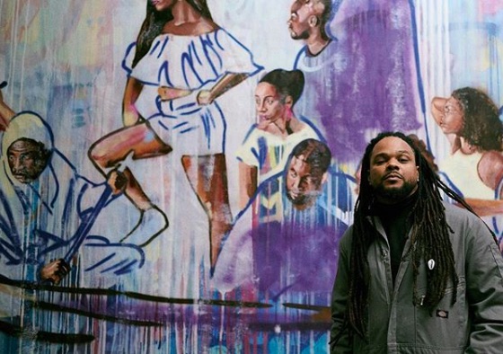 Bmike standing in front of one of his murals